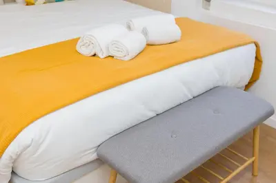 a bed with towels and a bench in a room at Cozy Studios Porto Sao Lazaro in Porto