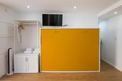a yellow door in a room with a tv on the wall at Cozy Studios Porto Sao Lazaro in Porto
