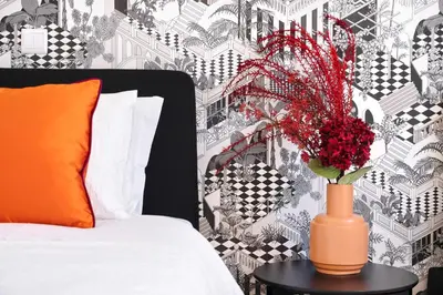 a vase with red flowers on a table next to a bed at 89 T3 - Flores Gem in Porto