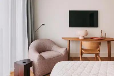 a bedroom with a chair and a table with a tv at LENSCAPE Coterie in Porto
