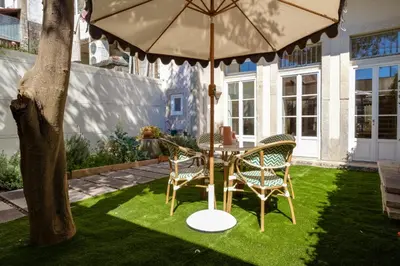 a table and chairs under an umbrella on a lawn at Garden Luxury House Downtown Oporto with AC in Porto