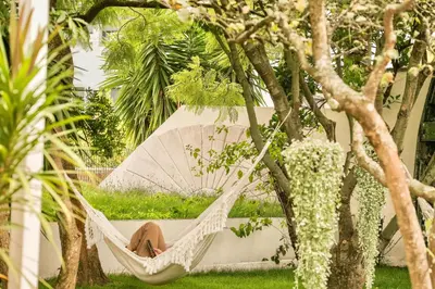 a dog sitting in a hammock in a hammock between trees at Porto Surf Lodge in Porto