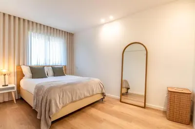a bedroom with a large bed and a mirror at Peaceful 1BR Near Metro by LovelyStay in Porto