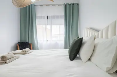 a bedroom with a white bed with pillows and a window at Purely Porto in Porto