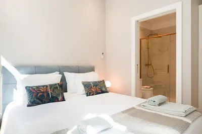 a bedroom with a white bed and a shower at Oliveirinhas Boutique Flats in Porto