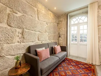a living room with a couch and a stone wall at Porto Stay for 3 near Ribeira in Porto