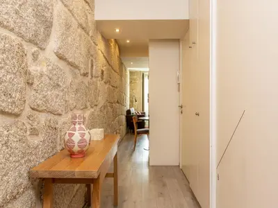 a vase sitting on a wooden table next to a stone wall at Porto Stay for 3 near Ribeira in Porto