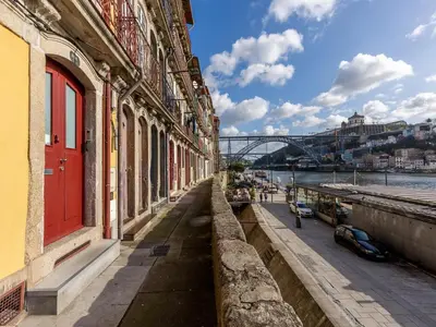 a building with a red door next to a river at Porto Stay for 3 near Ribeira in Porto