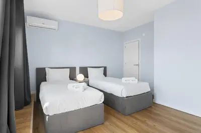 two beds in a room with white walls and wood floors at GuestReady – Urban comfort in Vila Nova de Gaia in Vila Nova de Gaia