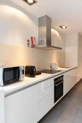 a white kitchen with a microwave and a sink at Porto Pátio by MP in Porto
