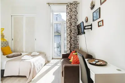 a small bedroom with a bed and a desk and a table at Cimo Apartments - Center Porto in Porto