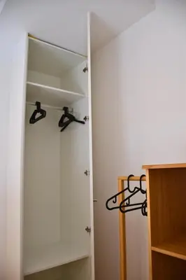 a closet with a white door and black hangers at O Refúgio das Caves by Horizon View Madeira in Vila Nova de Gaia