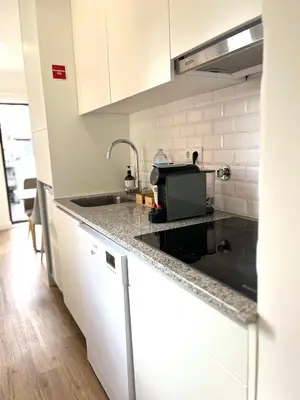 a kitchen with white cabinets and a sink at Historic Porto Flat I Balcony & Views by MyMoradia in Porto