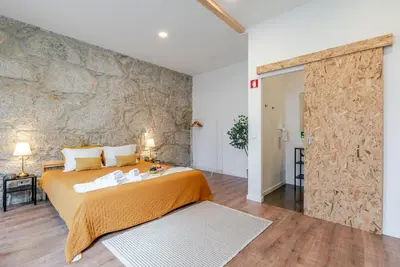 a bedroom with a large bed and a stone wall at DesKanzo Guest House - Raúl Doria in Porto