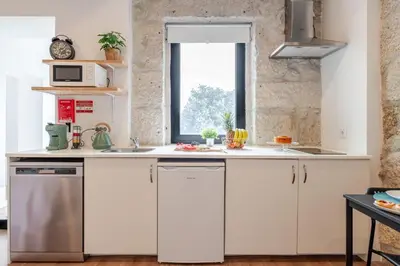 a kitchen with white cabinets and a window at DesKanzo Guest House - Raúl Doria in Porto