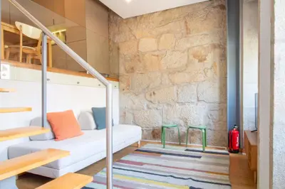 a room with a white couch and a brick wall at Bright 1BR with Parking in Bolhão by LovelyStay in Porto