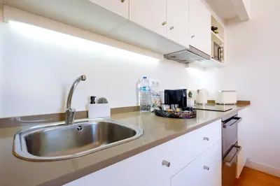 a kitchen with a stainless steel sink and white cabinets at Duque Luxury in Porto