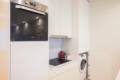 a kitchen with white cabinets and a washer and dryer at Luxury Style 20 with AC Downtown Porto near Metro in Porto