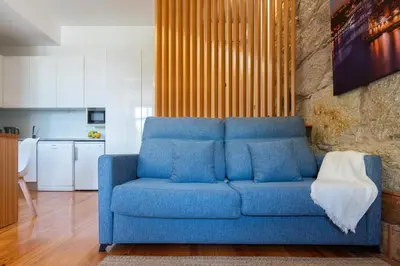 a blue couch sitting in a living room at Cozy Studio with Workspace by HostWise in Porto