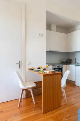 a kitchen with a table and two white chairs at Cozy Studio with Workspace by HostWise in Porto