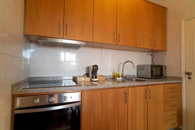 a kitchen with wooden cabinets and a sink and a stove at São João by Casa de Gondomil in Porto