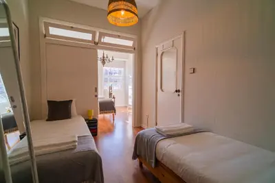 a room with two beds and a hallway with a window at São João by Casa de Gondomil in Porto