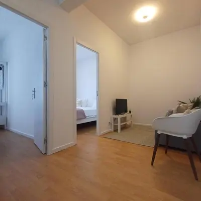 an empty living room with a white chair and a bedroom at Your Home in Porto 1480 Style and Comfort in Porto