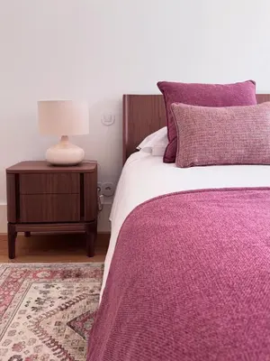 a bed with a purple blanket and a lamp on a table at My Home is Yours in Porto