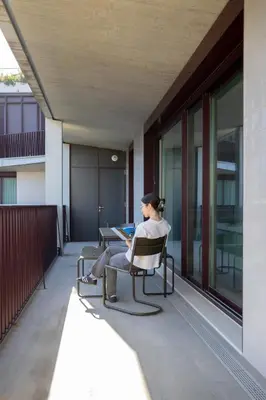 a woman sitting in a chair on a balcony with a laptop at My Home is Yours in Porto