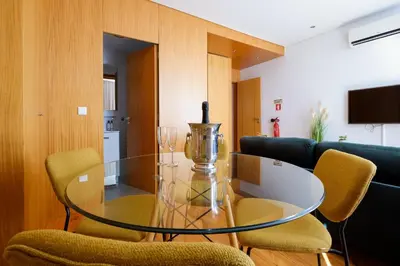 a glass table and chairs in a living room at Trindade Essence Duo Suites in Porto
