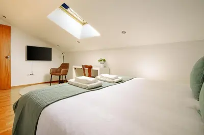 a bedroom with a large white bed with a skylight at Trindade Essence Duo Suites in Porto