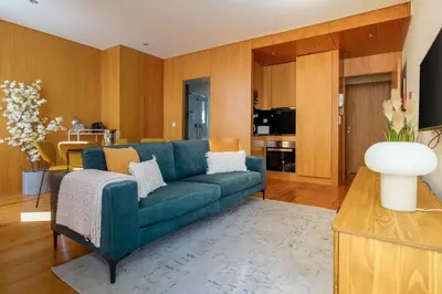 a living room with a blue couch and a kitchen at Trindade Essence Duo Suites in Porto
