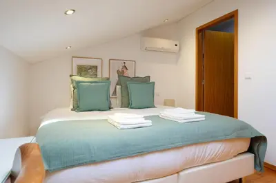 a bedroom with a bed with blue and green pillows at Trindade Essence Duo Suites in Porto