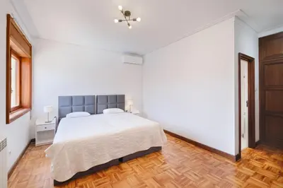 a white bedroom with a bed and a wooden floor at Villa 7BR & 7BA with Pool & Backyard in a Prime Location! in Vila Nova de Gaia