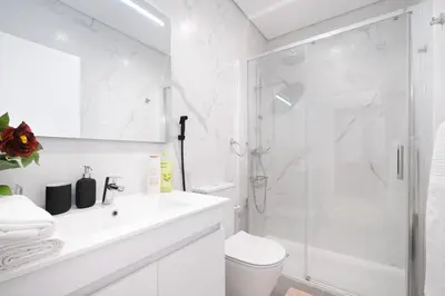 a white bathroom with a shower and a sink at Villa 7BR & 7BA with Pool & Backyard in a Prime Location! in Vila Nova de Gaia