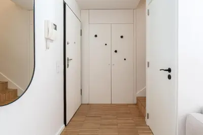 a hallway with white doors and a mirror at Stylish Open-Plan Flat with Swimming Pool by HostWise in Porto