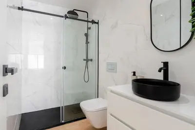 a bathroom with a glass shower and a black sink at Urban Terrace & Stylish Living Spaces by HostWise in Porto