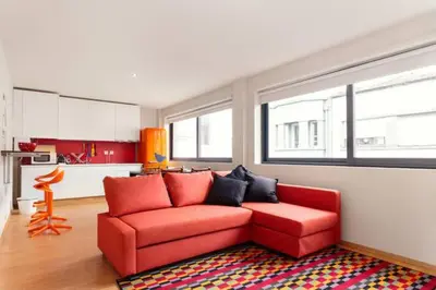 a living room with a red couch and a kitchen at Picaria Apartment in Porto