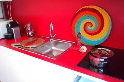 a kitchen counter with a sink and a red wall at Picaria Apartment in Porto