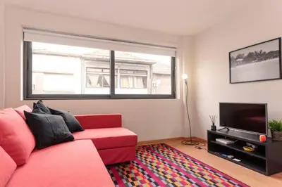 a living room with a red couch and a television at Picaria Apartment in Porto
