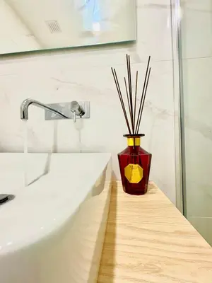 a red vase with sticks in it sitting next to a sink at Water VibesI City Views in Porto by MyMoradia in Porto