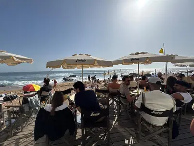 a group of people sitting at a beach with umbrellas at Water VibesI City Views in Porto by MyMoradia in Porto