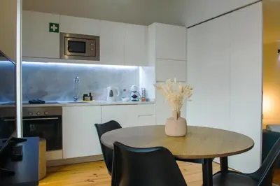 a kitchen with a table with a vase of flowers on it at Belas Artes Apartments in Porto