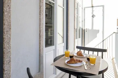 a table with food on a balcony with orange juice at ApartmentsPorto - Alexandre Braga in Porto
