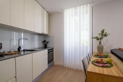 a kitchen with white cabinets and a wooden table at Santa Catarina Studio w Patio by LovelyStay in Porto