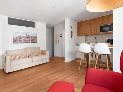 a living room with a white couch and a kitchen at Gaia Bella Guest House in Vila Nova de Gaia