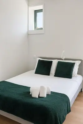 a large white bed with green and white pillows at Douro Vila 10 - Best View in Town in Bandeira