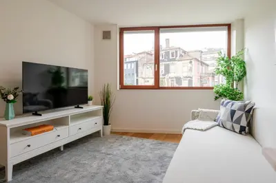 a white living room with a flat screen tv at Modern & Bright Flat in Cedofeita by HostWise in Porto