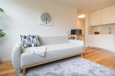a living room with a couch and a kitchen at Modern & Bright Flat in Cedofeita by HostWise in Porto