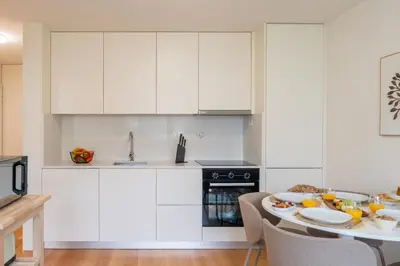 a kitchen with white cabinets and a table with food on it at Modern & Bright Flat in Cedofeita by HostWise in Porto